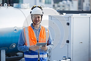 Asian man engineer holding tablet working at rooftop building construction. Male technician worker working checking hvac of office