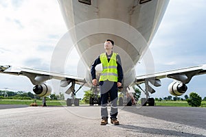 Asian man engineer maintenance airplane holding white helmet  in front airplane from repairs, fixes, modernization and renovation