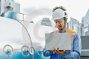 Asian man engineer using laptop checking valve working at rooftop building construction. Technician worker working checking hvac