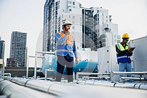 Asian man engineer using talkie walkie report working at rooftop building construction. Technician worker working checking hvac of
