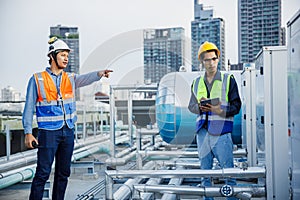 Asian man engineer working at rooftop building construction site. Technician worker working checking hvac of office building.