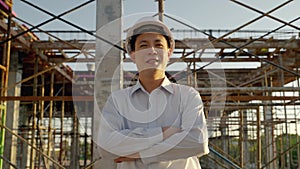 Asian man engineers are proudly in their company`s portfolio. Engineers stand and cross one`s arm inside the construction site. En