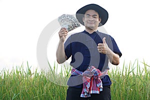 Asian man farmer is at paddy field, holds Thai banknote money and thumb up. Concept , Happy farmer get profit, income
