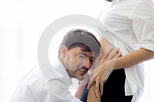 Asian man father ear listening to the belly of the pregnant wife to the movements of newbond.