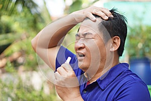 Asian man feel hot, unwell, use menthol inhaler to smell for relief symptom from hot weather.