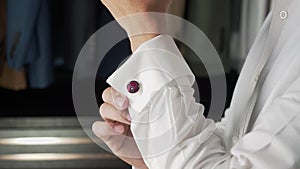 Asian man in formal dress adjusting cuff link at home closet. businessman grooming by wearing cufflinks.