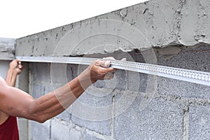 Asian man framing a wet concrete wall