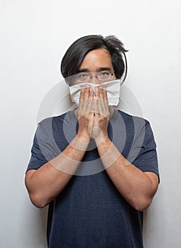 Asian man getting cold or flu,he is coughing to clear throat with hand holding tissue paper closing his mouth isolated on white