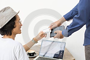 Asian man giving bank card ti pay bill with laptop and copy as background