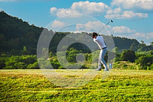 Asian man golfer standing holding and using wood driver to hitting golf ball from tee off to fairway on green grass