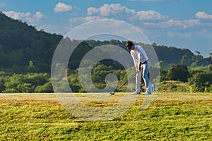 Asian man golfer standing holding and using wood driver to hitting golf ball from tee off to fairway on green grass