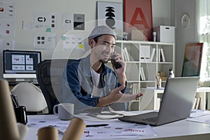 Asian man Graphic designer talking on mobile phone while working in office. Artist Creative Designer Graphic Skill Concept