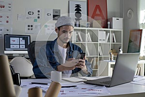 Asian man Graphic designer using smartphone while working in office. Artist Creative Designer Illustrator Graphic Skill Concept