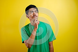 Asian man in green t-shirt thinking something, looking for good idea