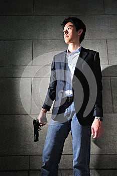 Asian Man with a Gun standing in the shadow
