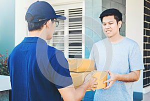 Asian Man hand accepting a delivery boxes from professional deliveryman at home