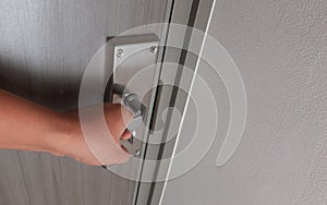 an asian man hand holding metal knob and trying to open door