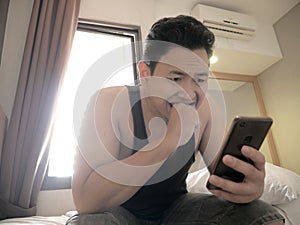 Asian man having bad news on phone when waking up on bed in the morning