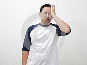 Asian man hitting his head, suffering from migraine headache or regret gesture