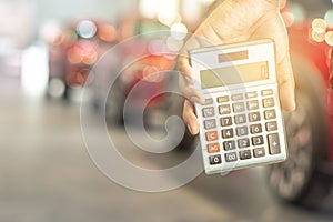 Asian man holding calculator for business finance on car showroom blurred bokeh background.for automotive automobile or