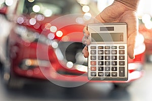 Asian man holding calculator for business finance on car showroom blurred bokeh background.for automotive automobile or
