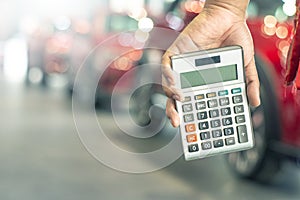 Asian man holding calculator for business finance on car showroom blurred bokeh background.for automotive automobile or