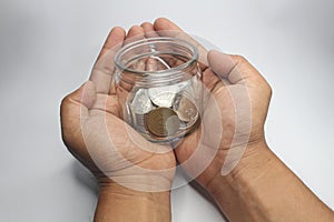 Asian man holding coins in a jar. Stock Photos.