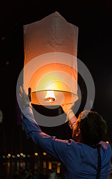 Asian man holding floating sky lanterns during Loy Kratong Festival