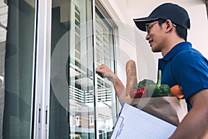 Asian man holding a food bag standing knocking at the front door