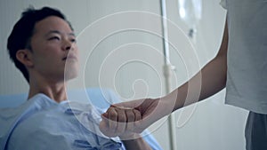 Asian man holding hand with his girlfriend encouragment during admit sick time in hospital room