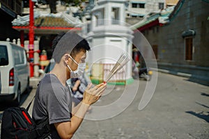 Asian man holding incense sticks and praying in a shrine photo
