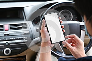 Asian man holding mobile phone while sitting in car.