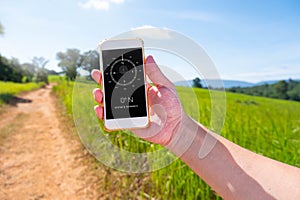 Asian man holding phone with compass in screen at the forest paths , tree , meadows , mountain and blue sky background