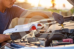 Asian man holding and reading the car user manual or user instruction to checking or fixing engine of modern car