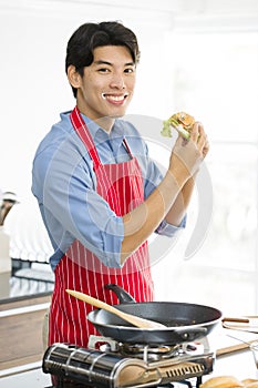 Asian man, he holds a hamburger and thumps up