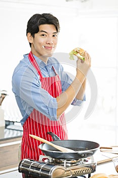 Asian man, he holds a hamburger and thumps up