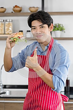Asian man, he holds a hamburger and thumps up