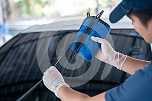 Asian man holds the microfiber in hand and wipe the windshield wipers the car, Car wash service concept