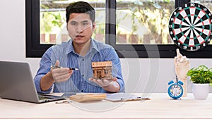 Asian man house sales representative working at desk with contract papers and calculator on desk real estate business ideas for ho