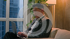 Asian man korean chinese japanese middle-aged businessman working remote internet typing on laptop writing business