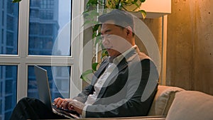 Asian man korean chinese japanese middle-aged businessman working remote internet typing on laptop writing business