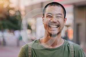 Asian man laughing while standing on a city street