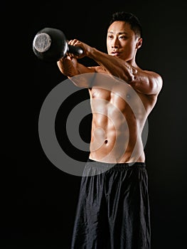 Asian man lifting a kettle bell