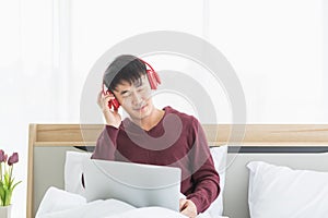 Asian man listen to music by headphone in bedroom