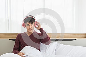 Asian man listen to music by headphone in bedroom