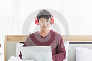 Asian man listen to music by headphone in bedroom