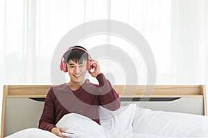 Asian man listen to music by headphone in bedroom