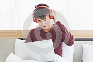 Asian man listen to music by headphone in bedroom