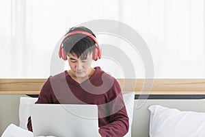 Asian man listen to music by headphone in bedroom