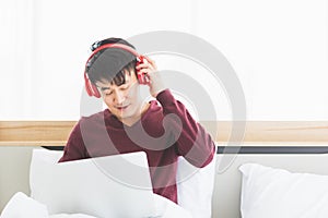Asian man listen to music by headphone in bedroom